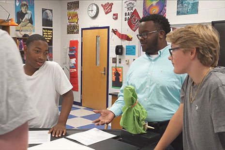 an African American teaching fellow leads a mixed group of students