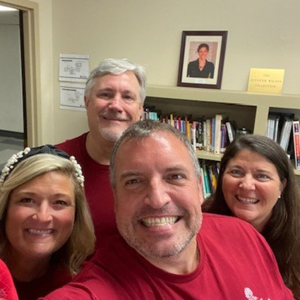 four people in red t-shirts smiling in a selfie