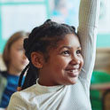 Black child raising a hand in classroom