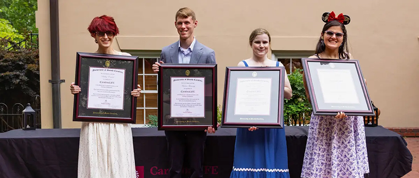 CarolinaLIFE students standing on the historic Horseshoe holding framed certificates