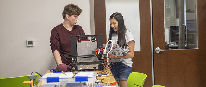 a grad student and undergrad student work on a 3d printer