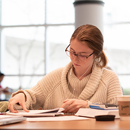 a female student works at a table with headphones in