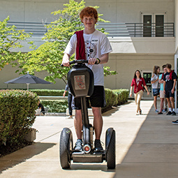 male student rides a segway in the courtyard