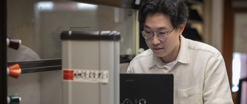 grad student looks at laptop in the lab