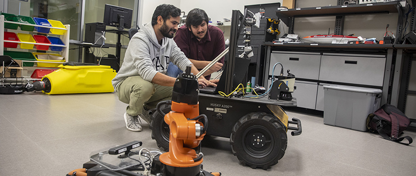 two students program a robot in a lab
