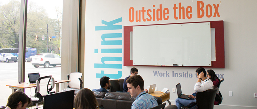 inside of the Innovation Think Tank Space with large windows and whiteboard and students working in groups