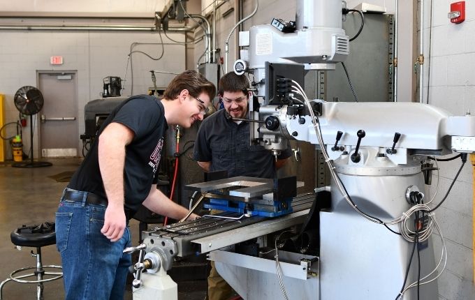 Student and machinist working on a machine in the shop.