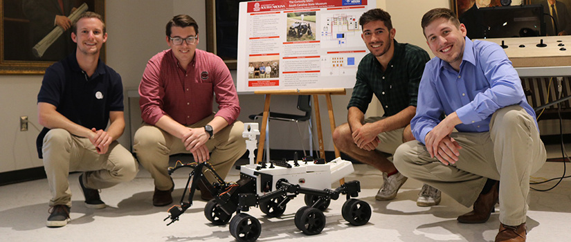 electrical enginerring students pose with mars rover prototype