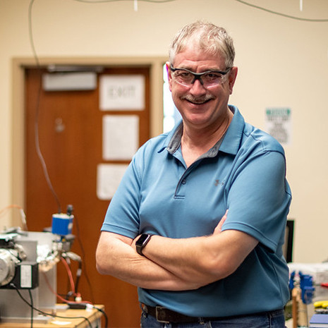 Dr. Lauterbach stands in his lab wearing saftey glasses