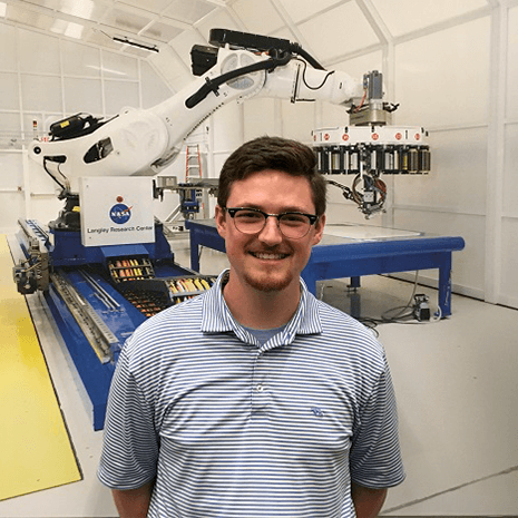 Jackson Swiney poses in front of a machine at NASA