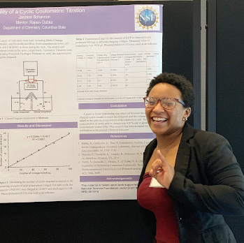 black woman stands next to her research poster