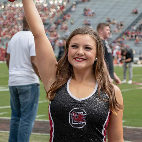 Abby Delnoce cheering as part of the dance team at a football game