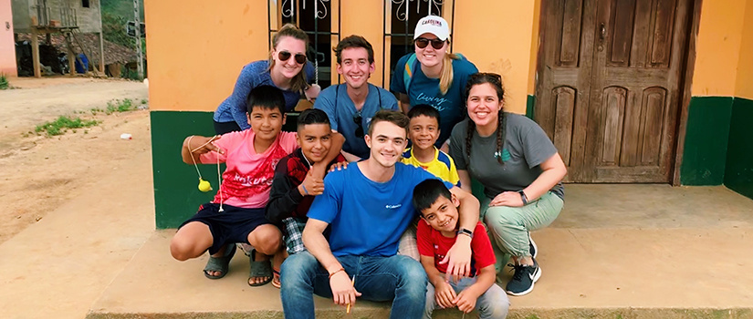 group of UofSC students poses with children in Ecuador