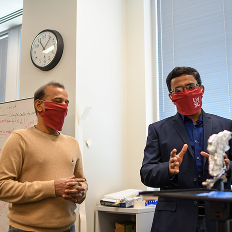 two professors talking wearing masks