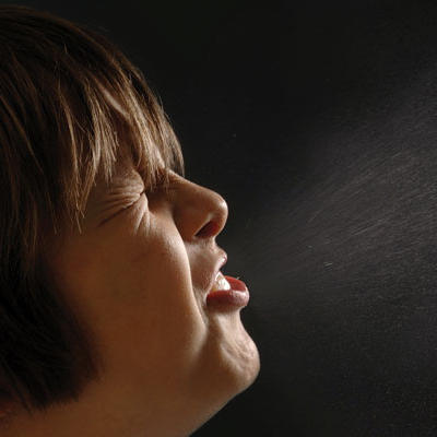 woman sneezing with visible droplets