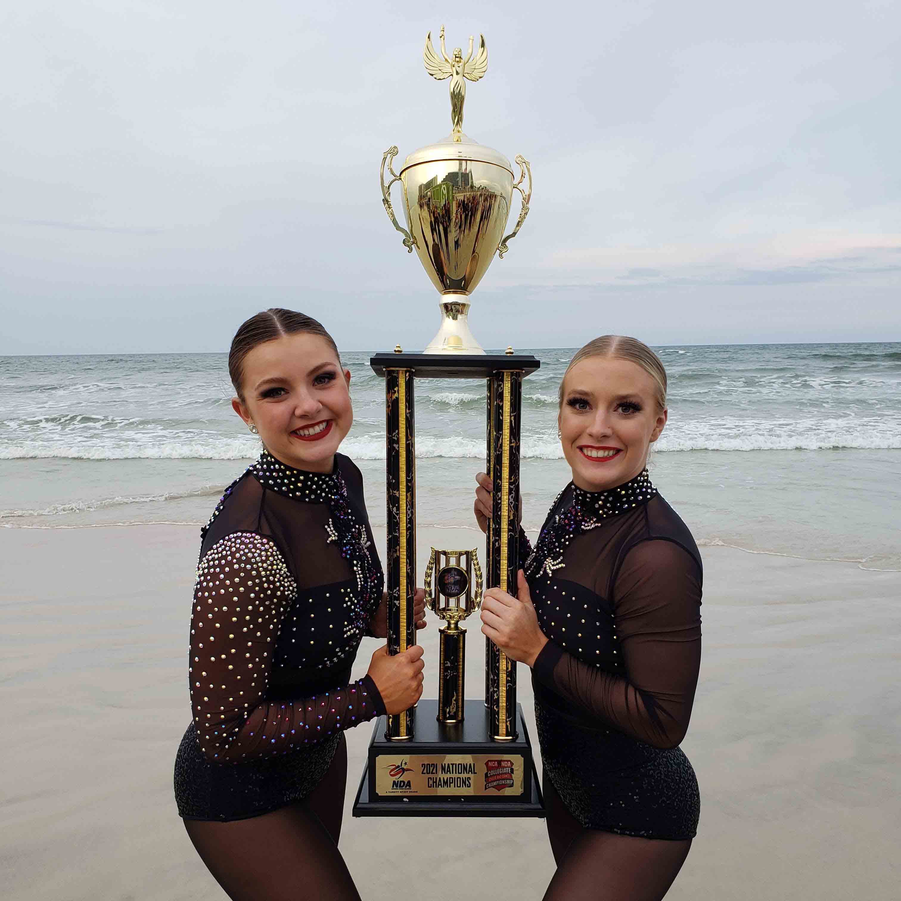 Morgan and Abby holding the trophy on the beah