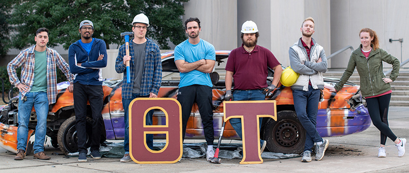 seven theta tau students wear hard hats and pose at the annual Clemson Car Smash