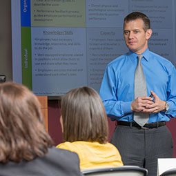 Man in tie makes a presentation to a class.