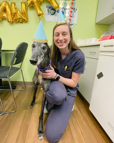 Young woman posing with a large dog. They are both wearing party hats.