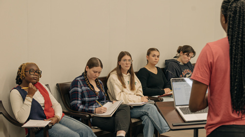 Group of students taking written notes on student presentation.