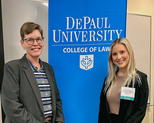 Two women standing in front of a blue banner that reads "DePaul University College of Law"