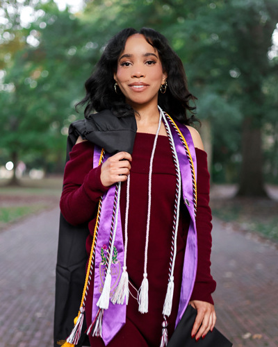 A young black woman in graduation regalia.