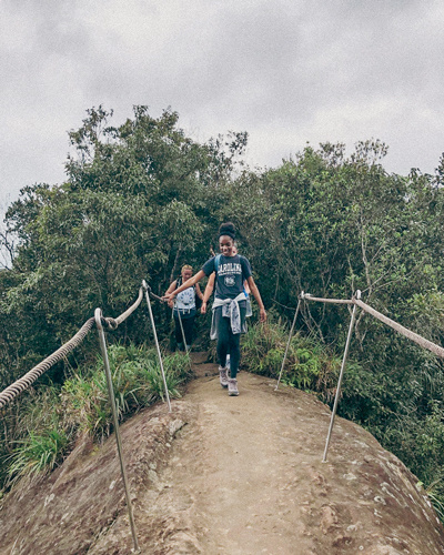 women hiking on dirt trail with greenery in the background