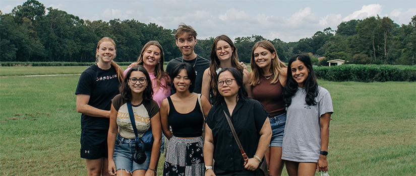 Group picture of students and professor Guo with a green field behind them.