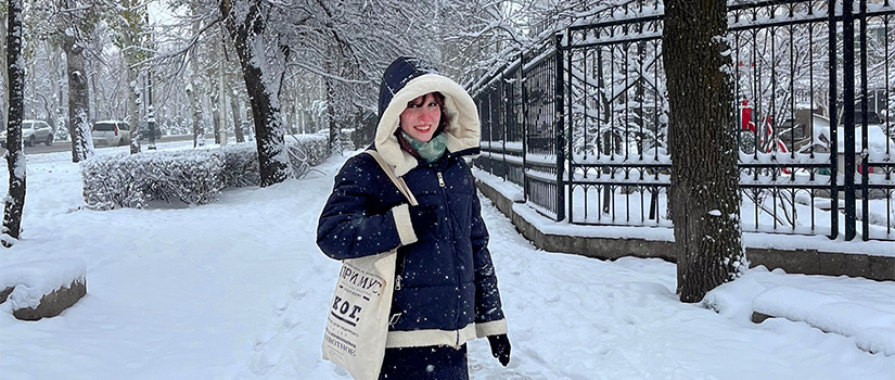 Woman smiling outside while it is snowing