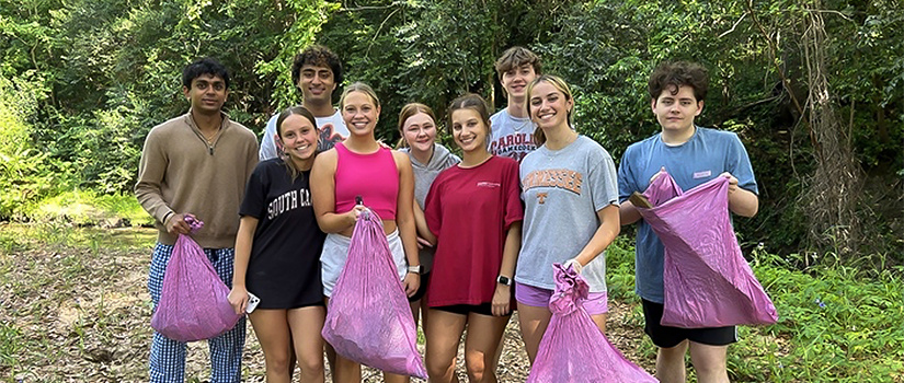 Group of students in Cocky's Cleanup Crew holding pink trash bags.