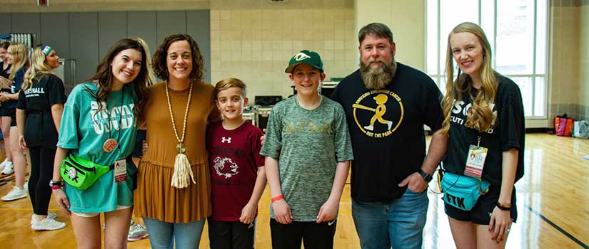 Sara Pollin stands with one of her "miracle families" in a gymnasium at the Dance Marathon Main Event 2019.