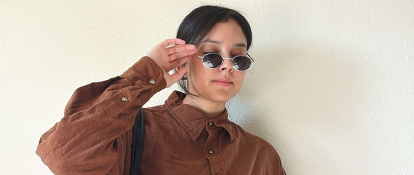 Alycia Elizabeth poses in a brown corduroy button-up, high-waisted denim shorts, and a woven tote bag, blending classic textures with modern flair.