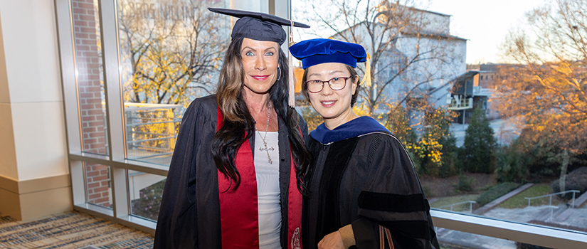 Elizabeth Moore Fox, first graduate of USC’s Master of Retail Innovation program, poses with program director Joohyung Park at the HRSM Degrees of Excellence ceremony in academic regalia.