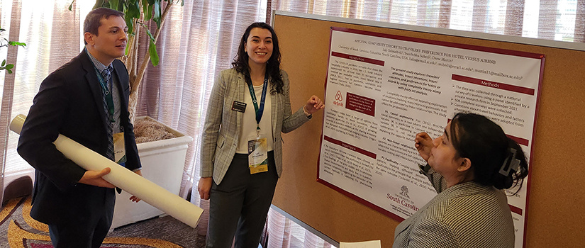 Two HRSM Ph.D. students present findings of their paper at a conference.