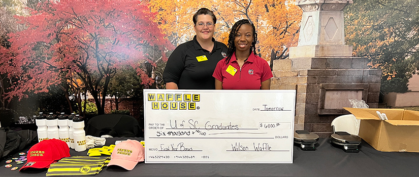 Two members of Waffle House display a large check for $6,000 for graduates.