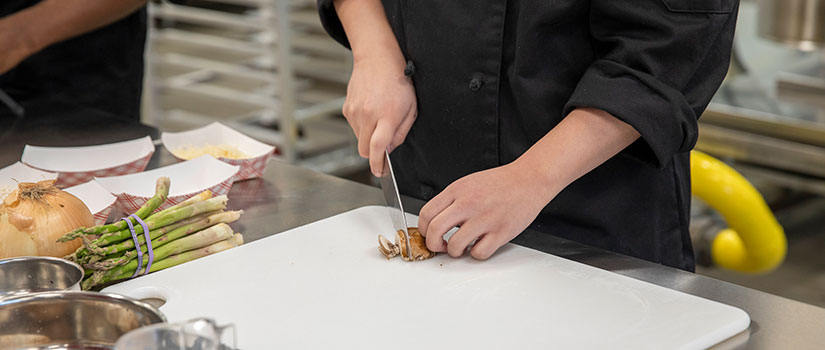 Close-up of hands slicing mushrooms in the state-of-the-art Marriott Culinary Lab