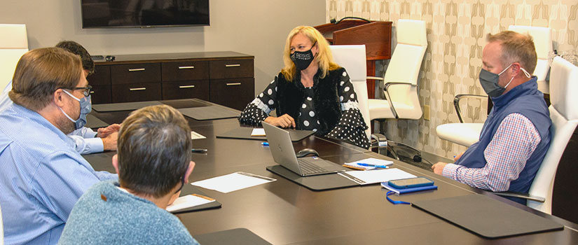 A group of HRSM researchers (Lori Pennington-Gray, David Cardenas, Todd Koesters) meet in HRSM's conference room.
