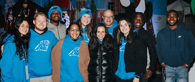 Nicole and David Tepper pose for a photo with several Tepper Scholars at a special holiday experience for deserving children and their families at Bank of America Stadium.