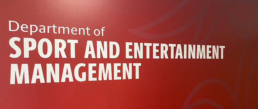Office entrance with a garnet background stating Department of Sport and Entertainment Management.