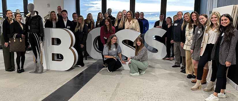Retailing students and faculty pose for a photo around large letters for the Hugo Boss brand at NYC Fashion Week 2023.