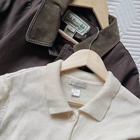 Close-up of vintage L.L. Bean and Paradox brand tops on wooden hangers.