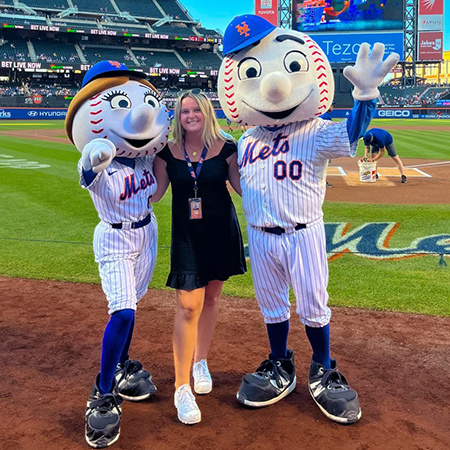 A student poses with Mr. and Mrs. Met, the mascots for the New York Mets baseball team.