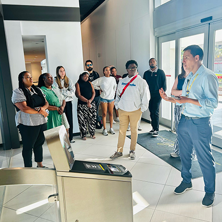 Students, faculty and staff listen to hotel representative during a guided tour