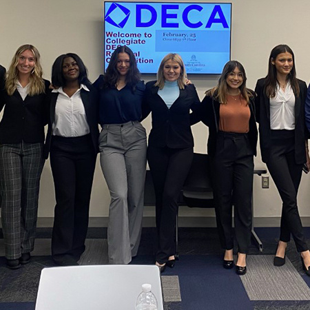 Six members of Collegiate DECA at USC pose for a photo at a regional competition held in the Close-Hipp building.
