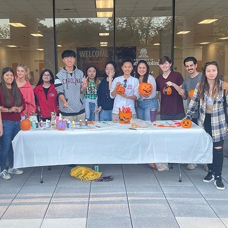 Members of the HRSM Global Community group pose for a photo outside the Close-Hipp building after a pumpkin carving and painting event.