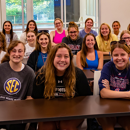 Members of the Women in Sport and Entertainment Club smile for the camera at a meeting.