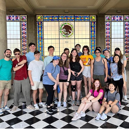 Students pose for a photo with associate professor Armen Shaomian while taking a tour in Mexico City.