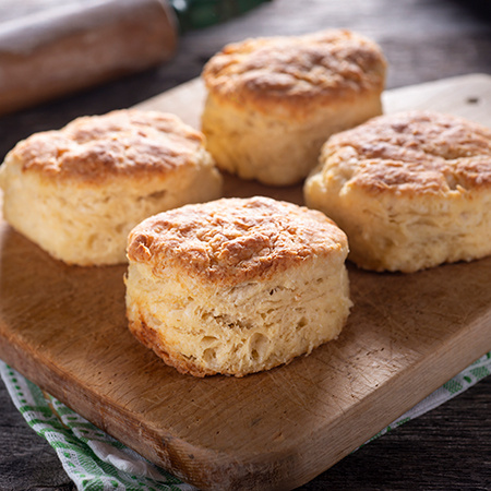 Four biscuits sit on a wooden serving plate