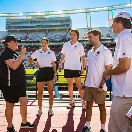 Four sport and entertainment management majors listen to instructions from a USC athletics administrator prior to working a football game in September 2022.