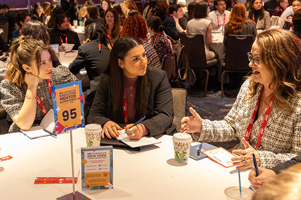 Two students sit at a table at a conference for a networking event